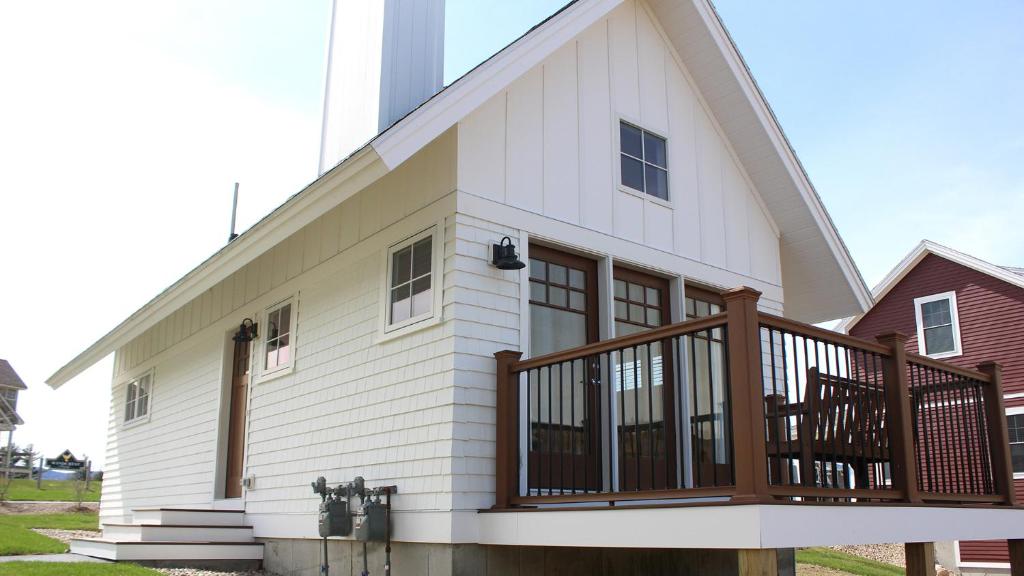 Casa blanca grande con balcón de madera en Owl's Nest Resort en Thornton