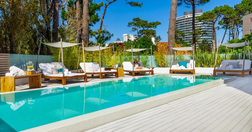 a swimming pool with chairs and tables next to a building at AWA Boutique + Design Hotel in Punta del Este