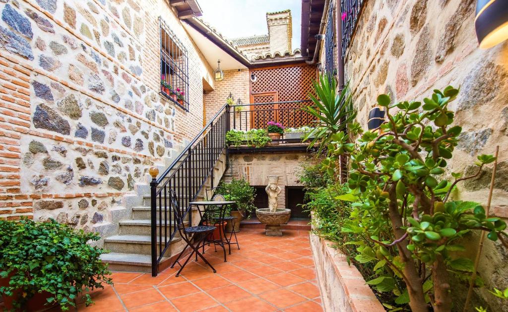 a courtyard with stairs and a table and chairs at Casa de Bisagra in Toledo