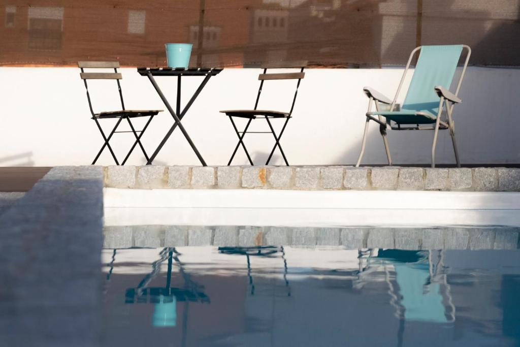 科英布拉的住宿－Casa dos Carvalhos，游泳池畔的两把椅子和一张桌子