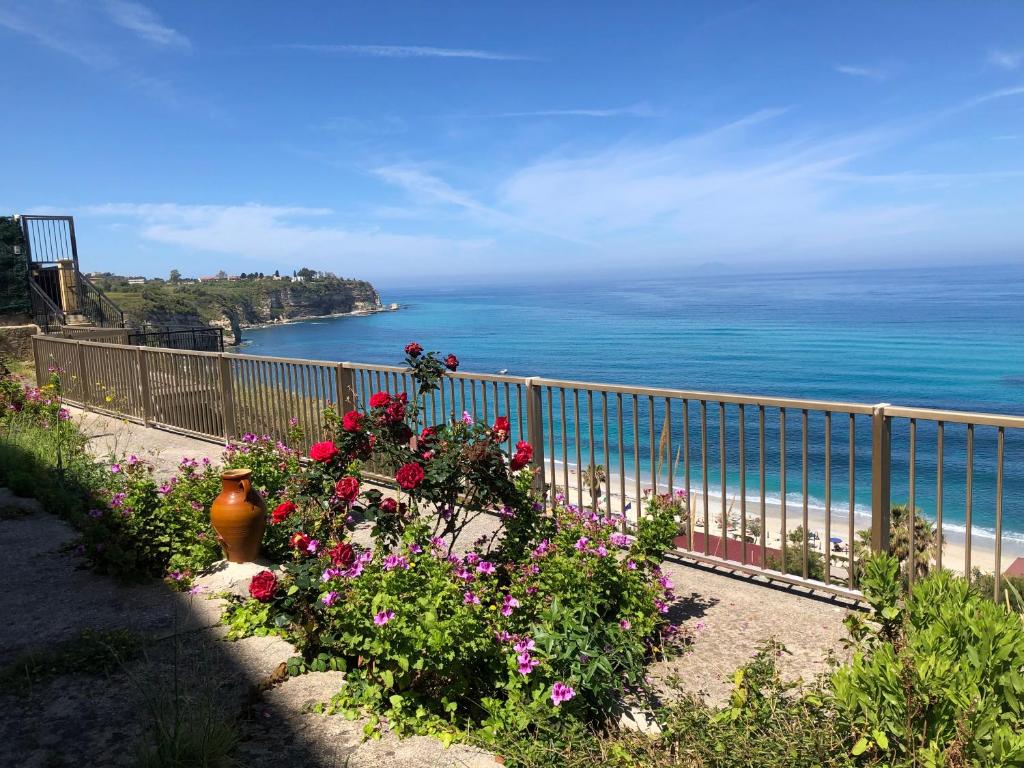 a view of the ocean from a balcony with flowers at LA MESONETTE A DUE PASSI DAL MARE in Tropea