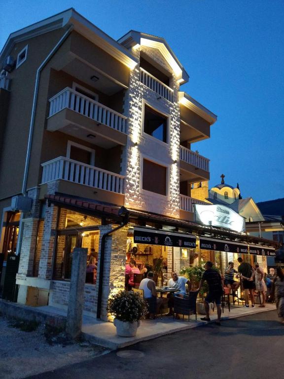 ein Gebäude mit Leuten, die draußen an Tischen sitzen in der Unterkunft Galiot Apartman in Ðenovići
