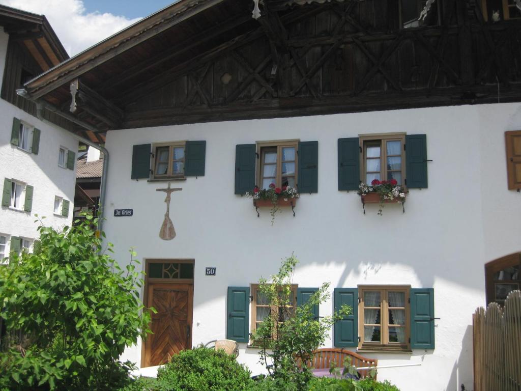 Casa blanca con persianas y ventanas verdes en Ferienhaus Bichler, en Mittenwald