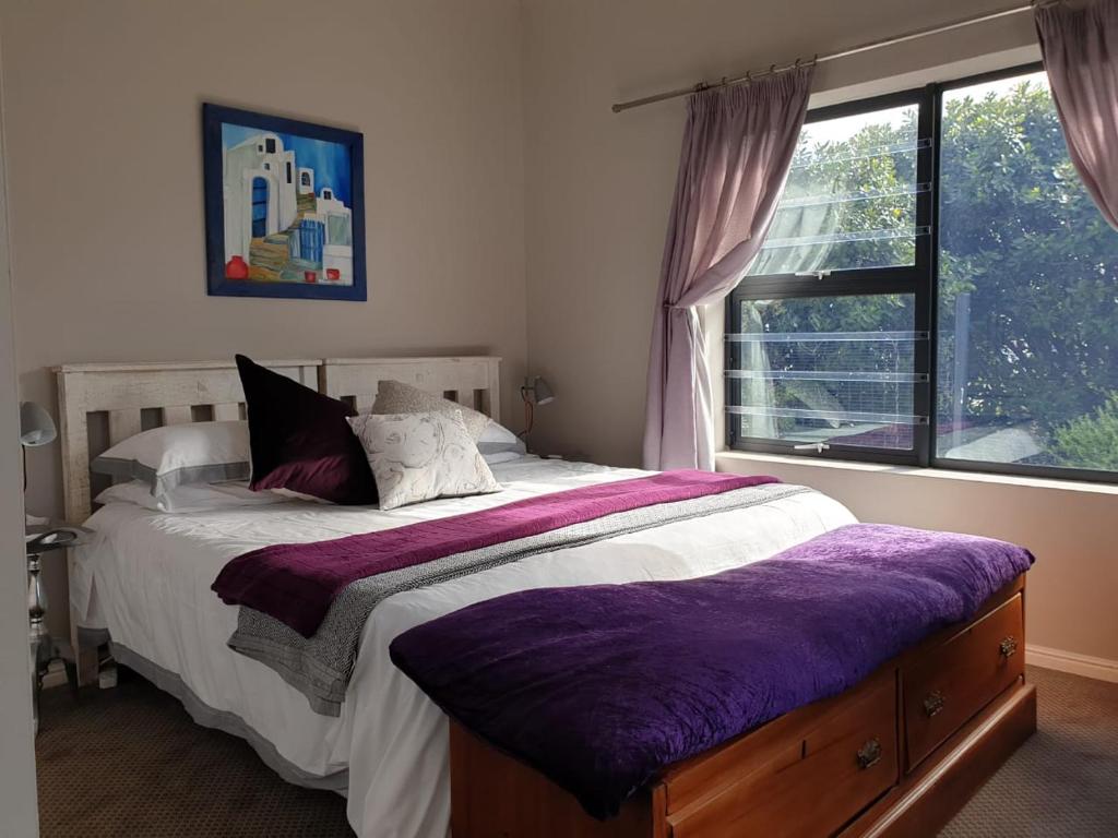 a bedroom with a large bed with a purple blanket at Indigo Place - Blue in Hermanus