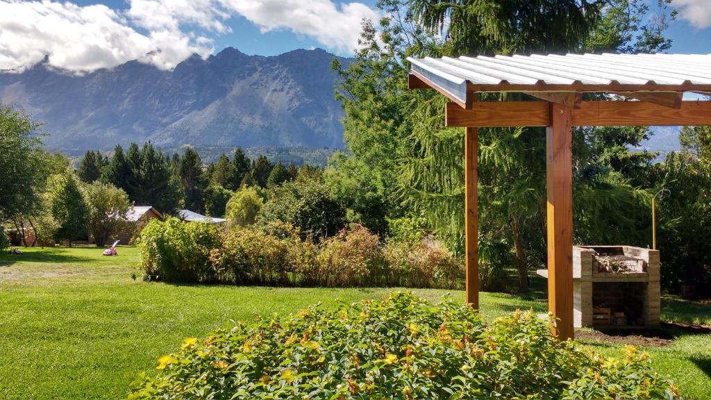 einen hölzernen Pavillon auf einem Feld mit Bergen im Hintergrund in der Unterkunft Cabañas San Valentin in Lago Puelo