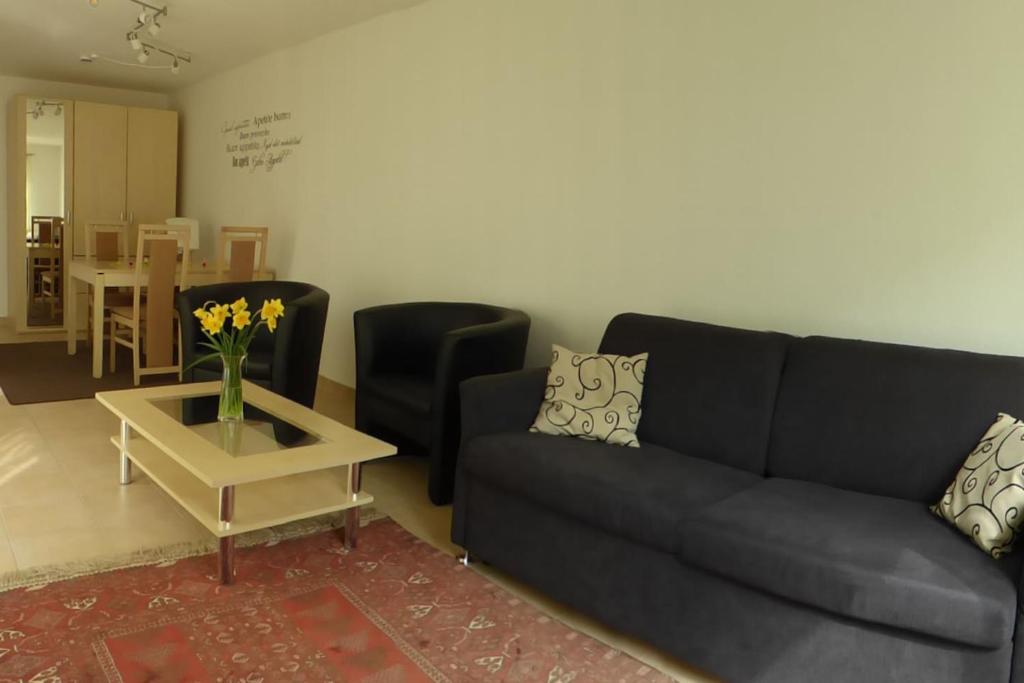 a living room with a black couch and a table at Gästewohnung nähe Messe/Flughafen in Filderstadt