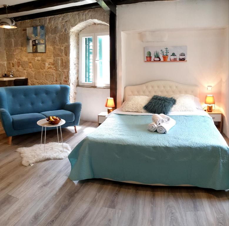 a bedroom with a blue bed and a blue couch at Heritage Apartments Trumbić in Split