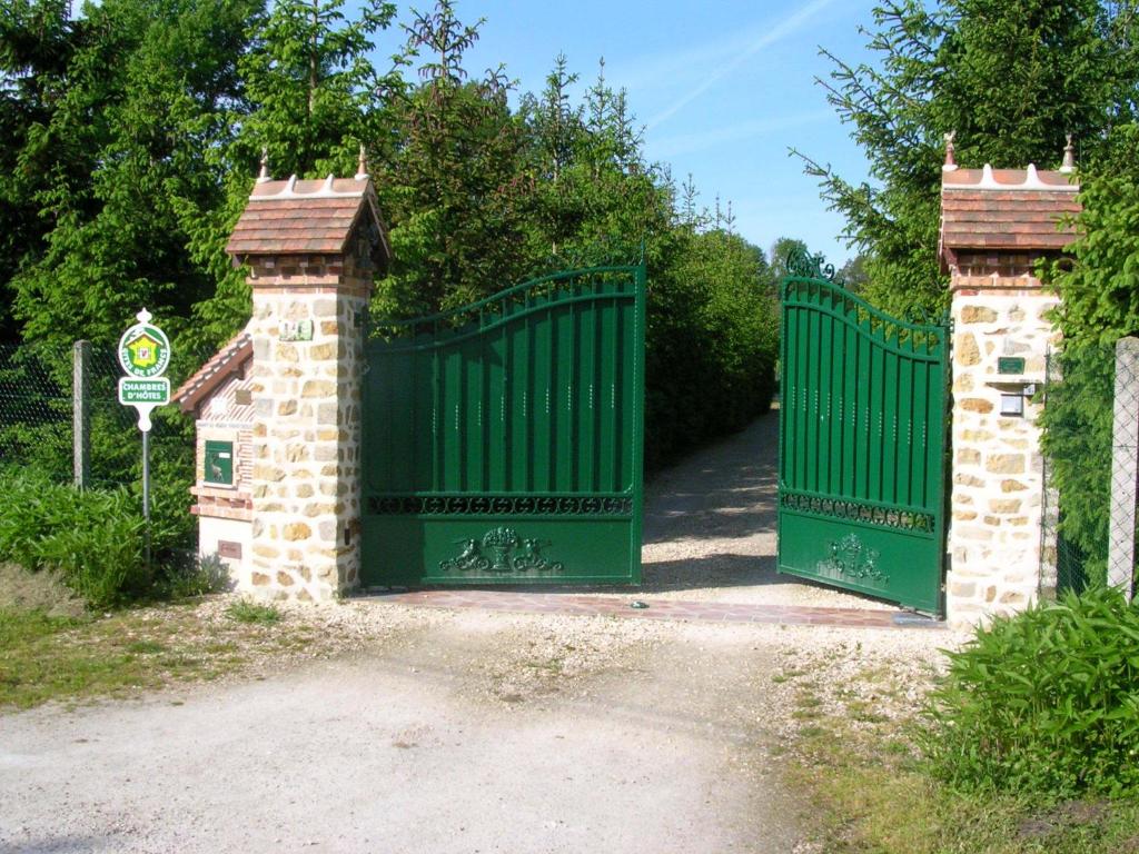 a green gate on a driveway with a sign at La Petite Ferme in Vouzeron