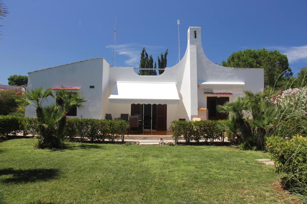 une maison blanche avec une pelouse devant elle dans l'établissement Villa Rosa Marina, à Rosa Marina