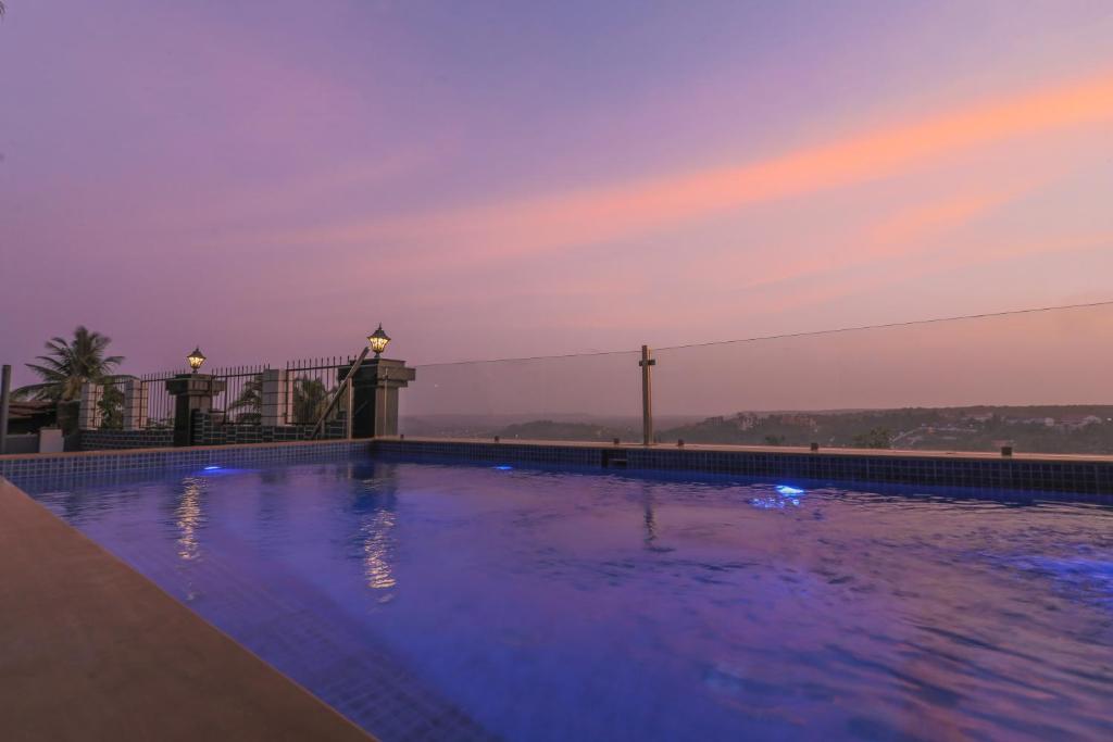 a swimming pool at dusk with a bridge in the background at Hill Top Luxury Villa - 3 BHK || Infinity Pool in Mapusa