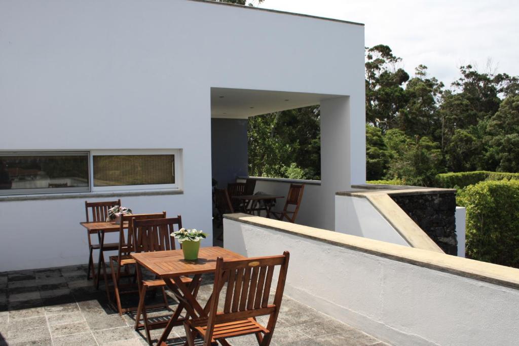 un patio con mesas de madera y sillas en el balcón en Quinta de São Caetano - São Miguel Açores en Populo