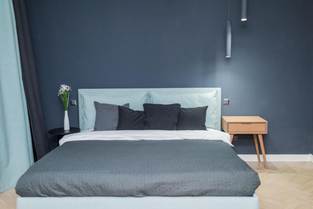 a blue bedroom with a large bed with gray pillows at Explore the City from Its Center in a Chic Balcony Apartment in Bucharest