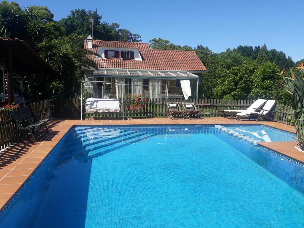 a blue swimming pool with a house in the background at El Atico de Villalmar in Tui