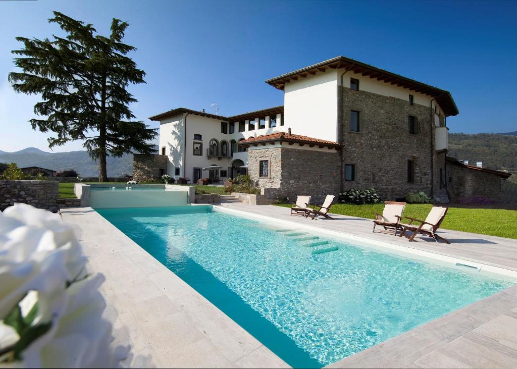 a villa with a swimming pool in front of a house at Podere Castel Merlo Resort in Villongo SantʼAlessandro