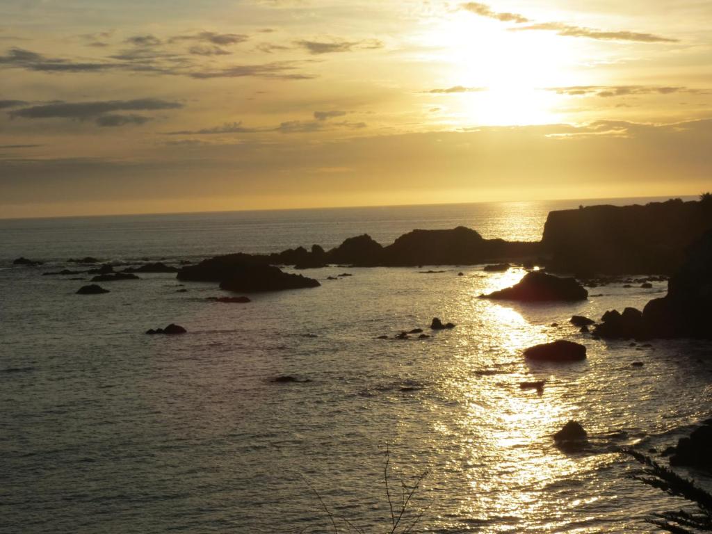 een zonsondergang boven de oceaan met rotsen in het water bij Tanbark Shores Guest Suite in Brookings