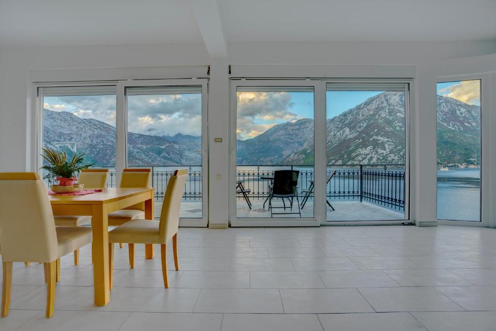 a dining room with a table and views of the mountains at Villa KOSTA in Donji Morinj