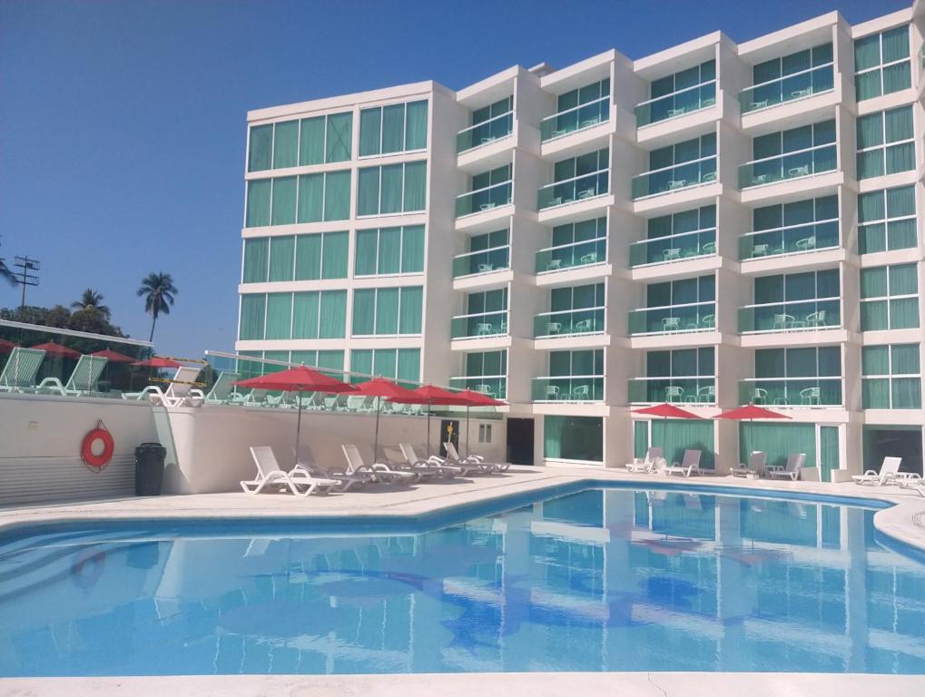 un hotel con piscina, sillas y un edificio en We Hotel Acapulco en Acapulco