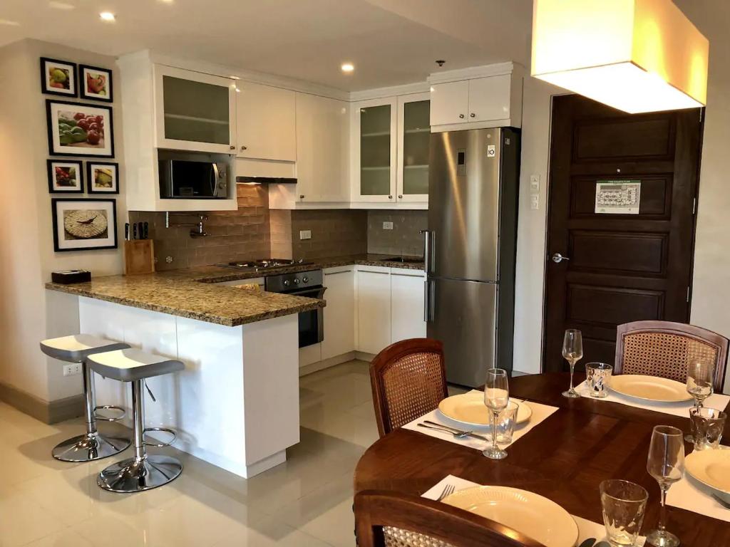 Una cocina con una mesa con sillas y un refrigerador. en 500Mbps Wi-Fi 2 Largest 2 BDRM Condo in Grand Residences, en Cebú