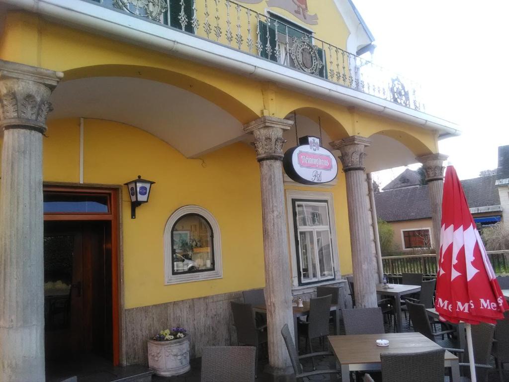 a yellow building with a table and a umbrella at Zur goldenen Krone in Ehrenhausen