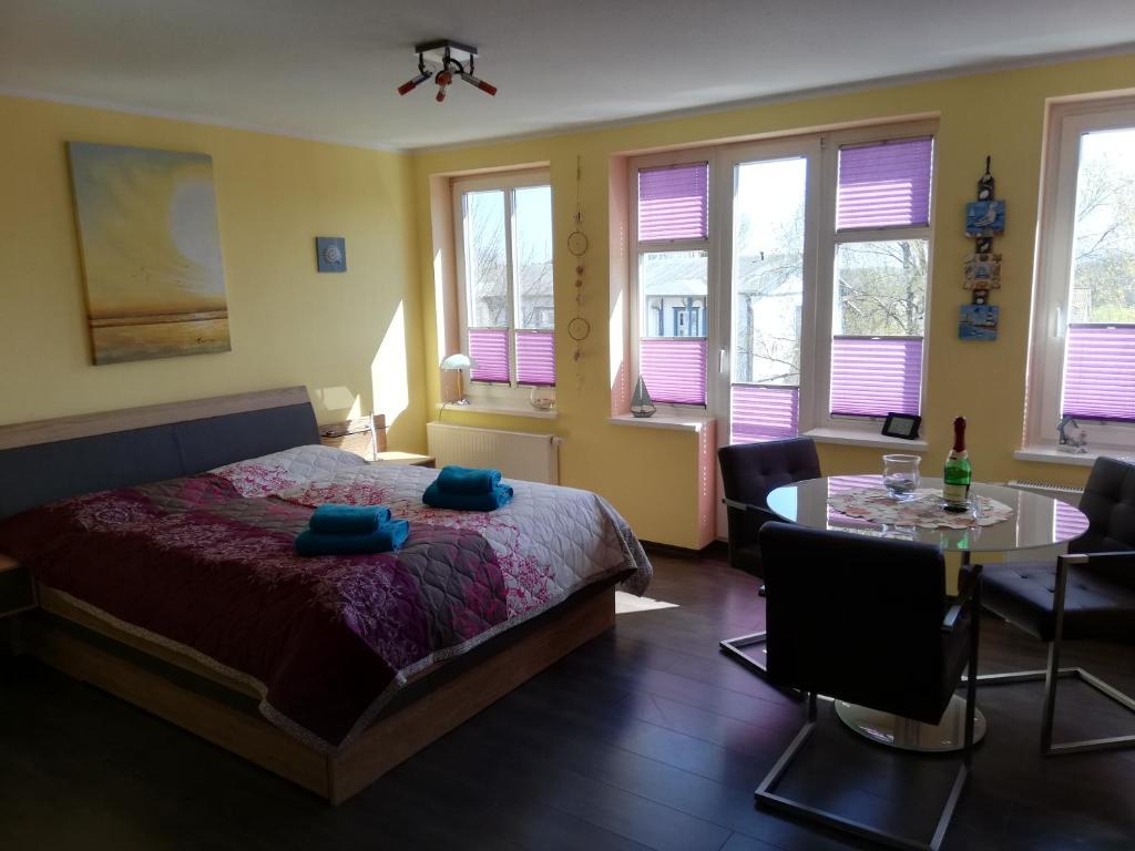Schlafzimmer mit einem Bett, einem Tisch und Fenstern in der Unterkunft Appartement Blaue Welle in Bansin