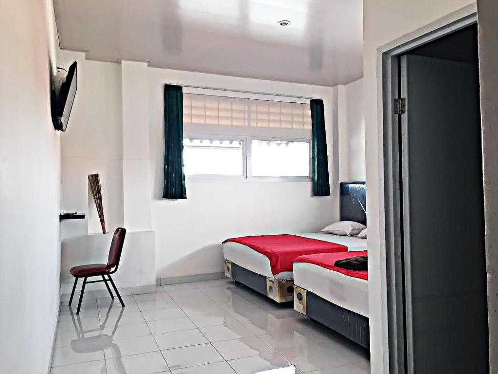 a bedroom with a bed and a chair and a window at Mitra Hotel in Yogyakarta