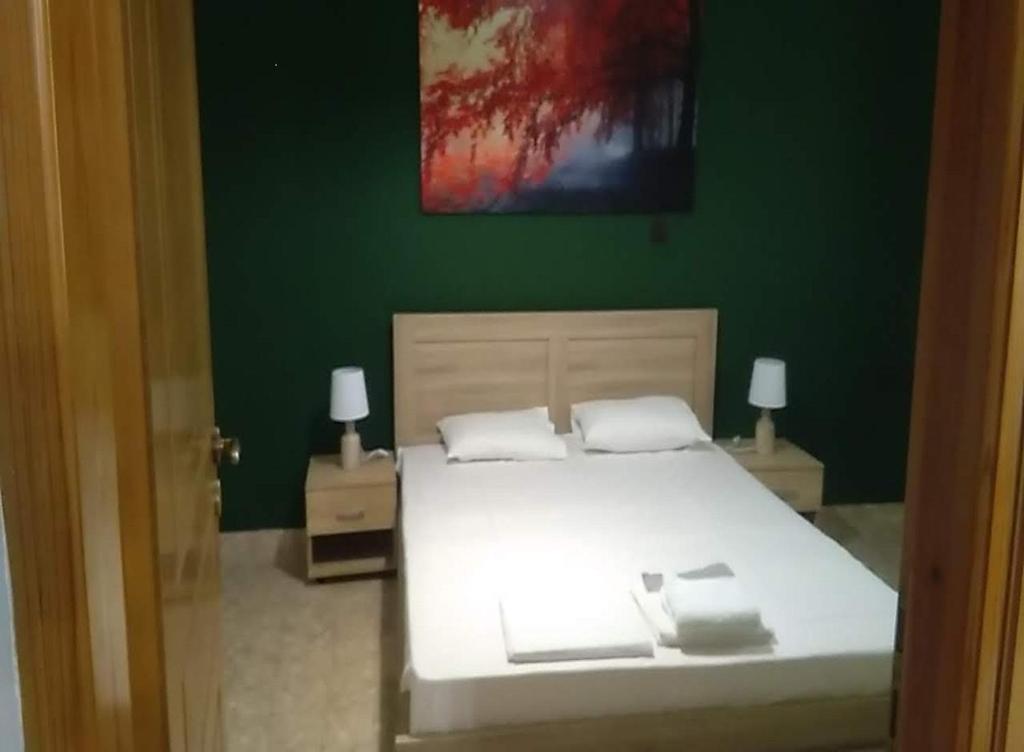 ein Schlafzimmer mit einem weißen Bett und einer grünen Wand in der Unterkunft Lemontree in Athen