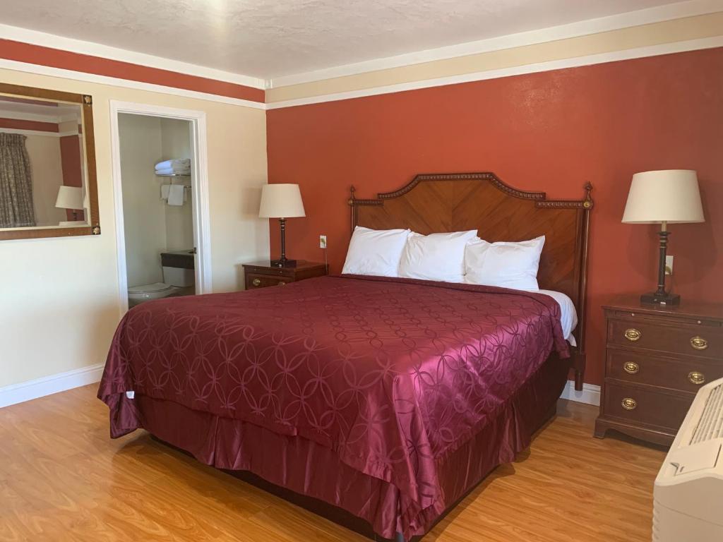 a bed in a hotel room with a red wall at Wagon Wheel Motel in Salinas