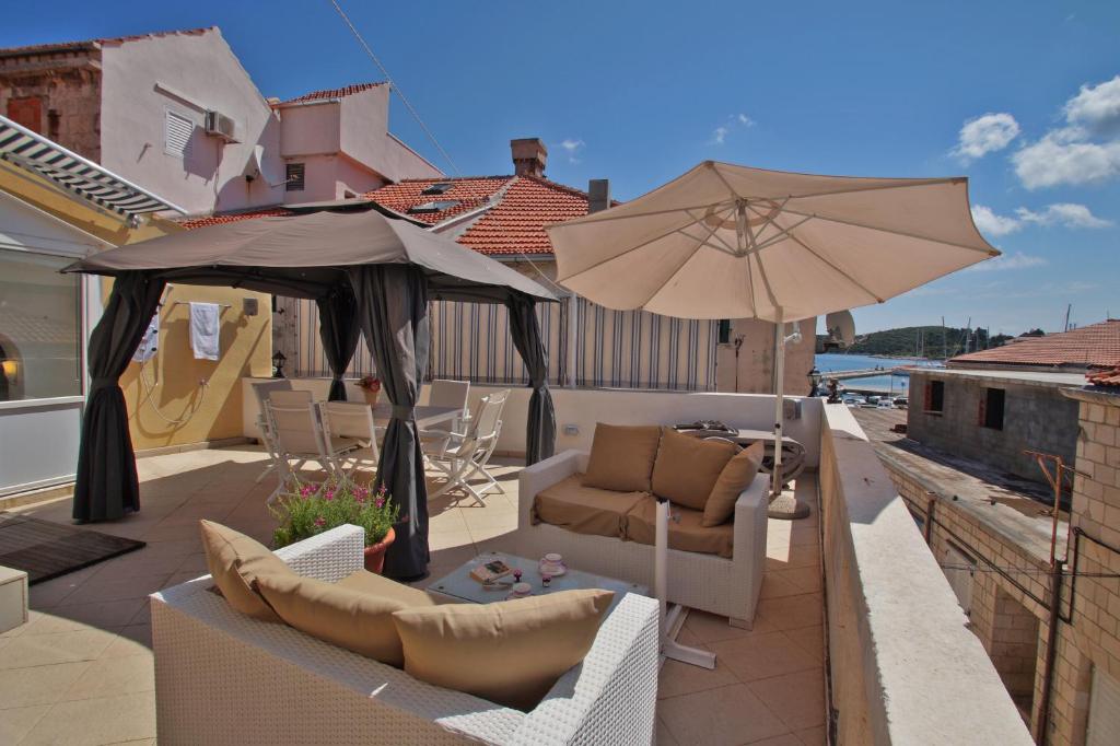 un patio con sillas y una sombrilla en el techo en Apartments Galerija, en Korčula