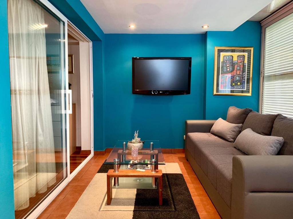 a living room with a couch and a tv on a blue wall at Guest House Amalija in Dubrovnik