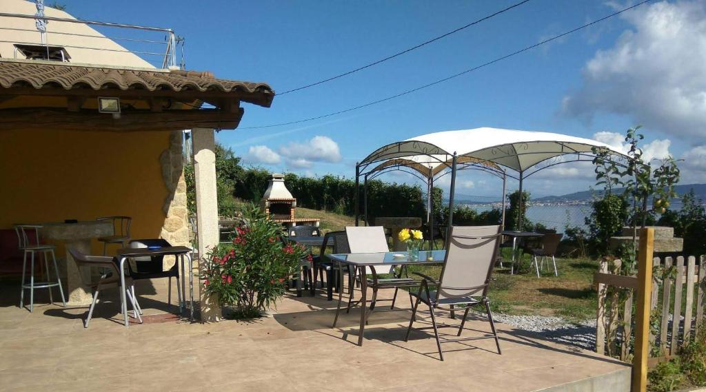 un patio con mesa, sillas y sombrillas en Vilar Norte, en Bueu