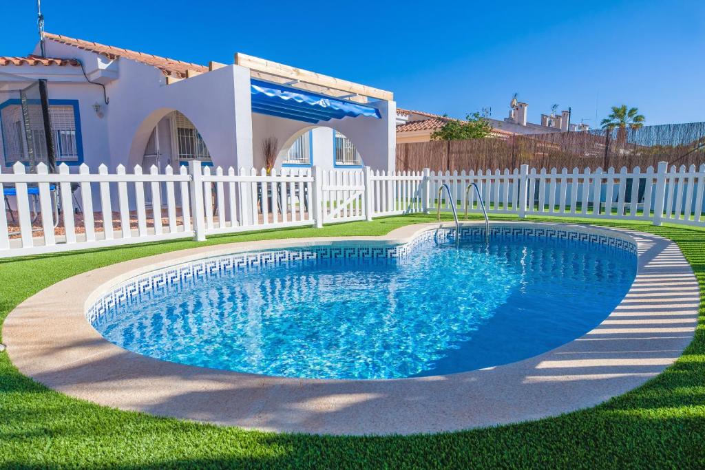 ein Schwimmbad in einem Garten neben einem weißen Zaun in der Unterkunft Villa Julia in Riumar