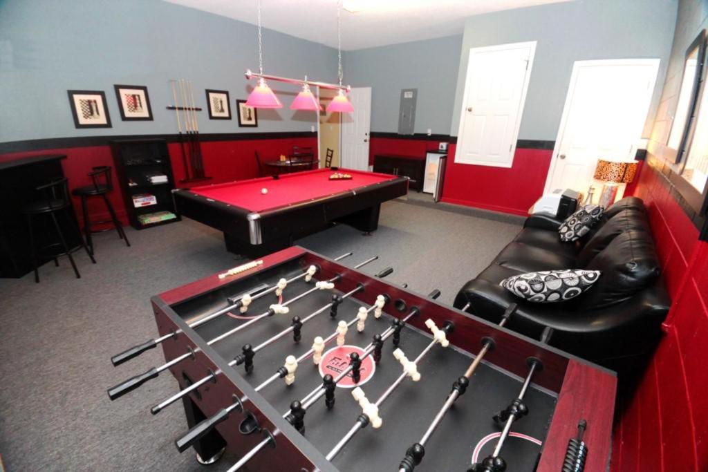 ein Wohnzimmer mit einem roten Billardtisch mit Hockeyschlägern in der Unterkunft 301 Las Fuentes Drive Home in Kissimmee