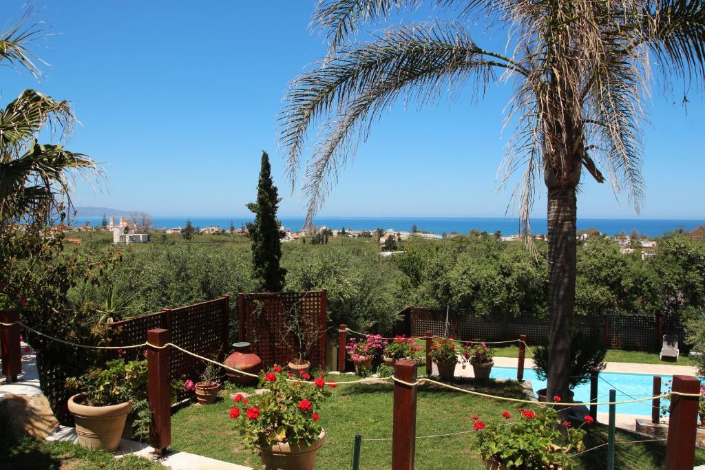 un jardín con piscina, palmeras y flores en Villa Palma, en Máleme