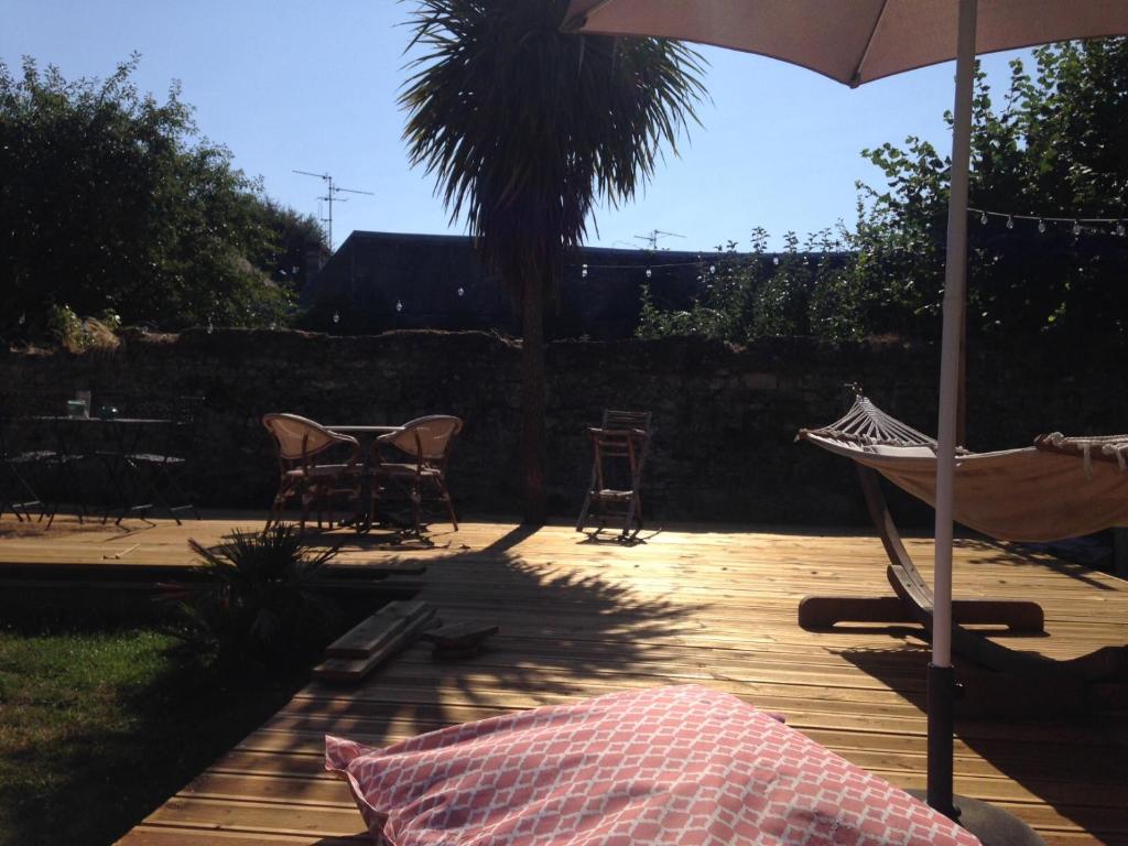 un patio avec une table, des chaises et un parasol dans l'établissement Chalet Camélia Bayeux centre-ville, à Bayeux