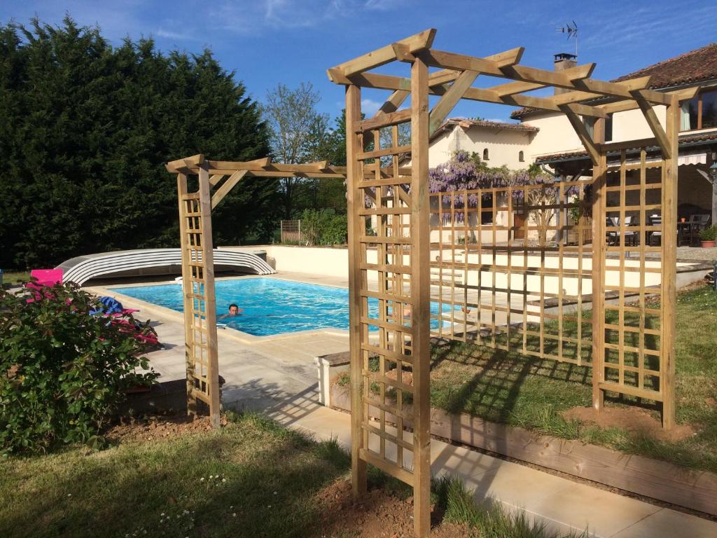 een houten pergola naast een zwembad bij Wisteria & Jasmine in Génouillé