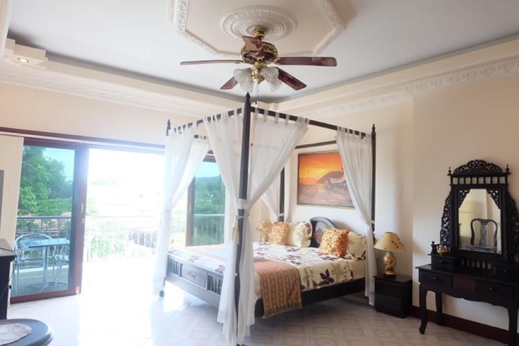 a bedroom with a bed with a ceiling fan at Majestic Villas Guesthouse Phuket. in Rawai Beach