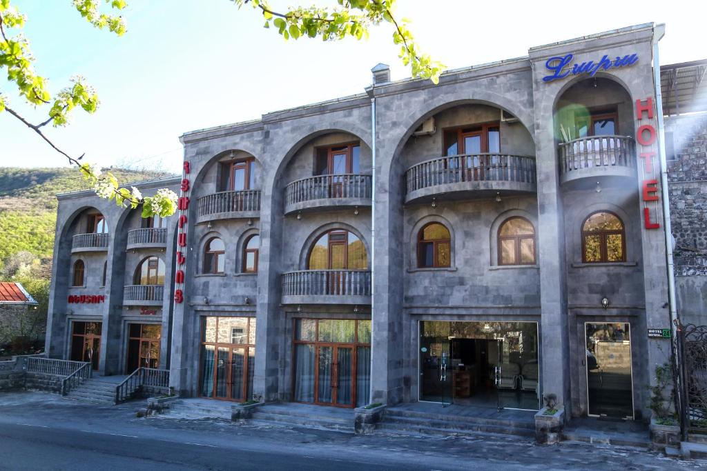 ein großes Steingebäude mit Balkonen auf einer Straße in der Unterkunft Lara Hotel in Goris