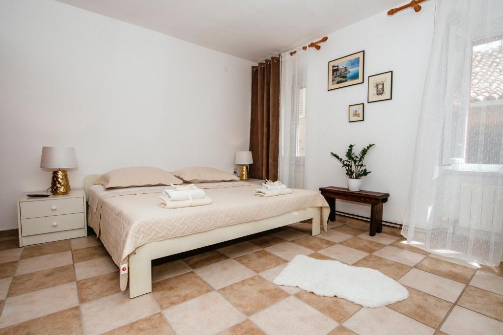 a white bedroom with a bed and a window at Heart of Town in Zadar
