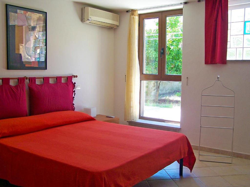 a bedroom with a red bed and a window at Casa Liliana in Oristano