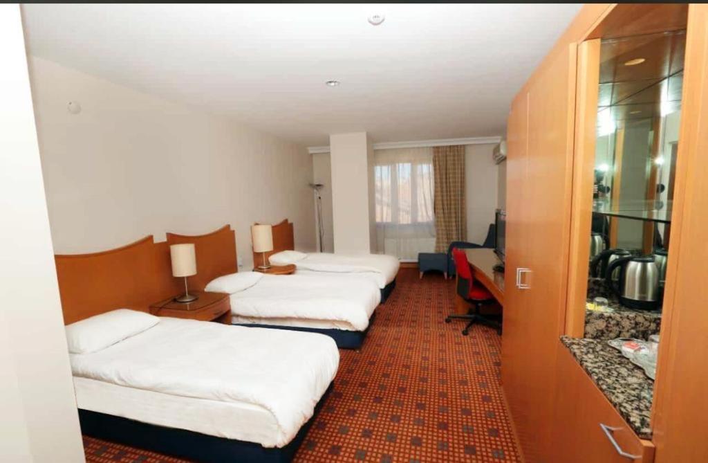 ディヤルバクルにあるDiyarbakır otelのベッド3台と机があるホテルの部屋