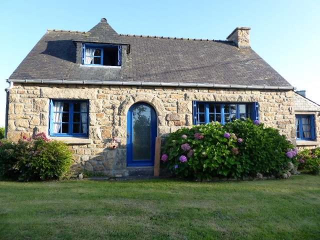 a stone house with a blue door and some flowers at Natursteinhaus in Portsall in Ploudalmézeau