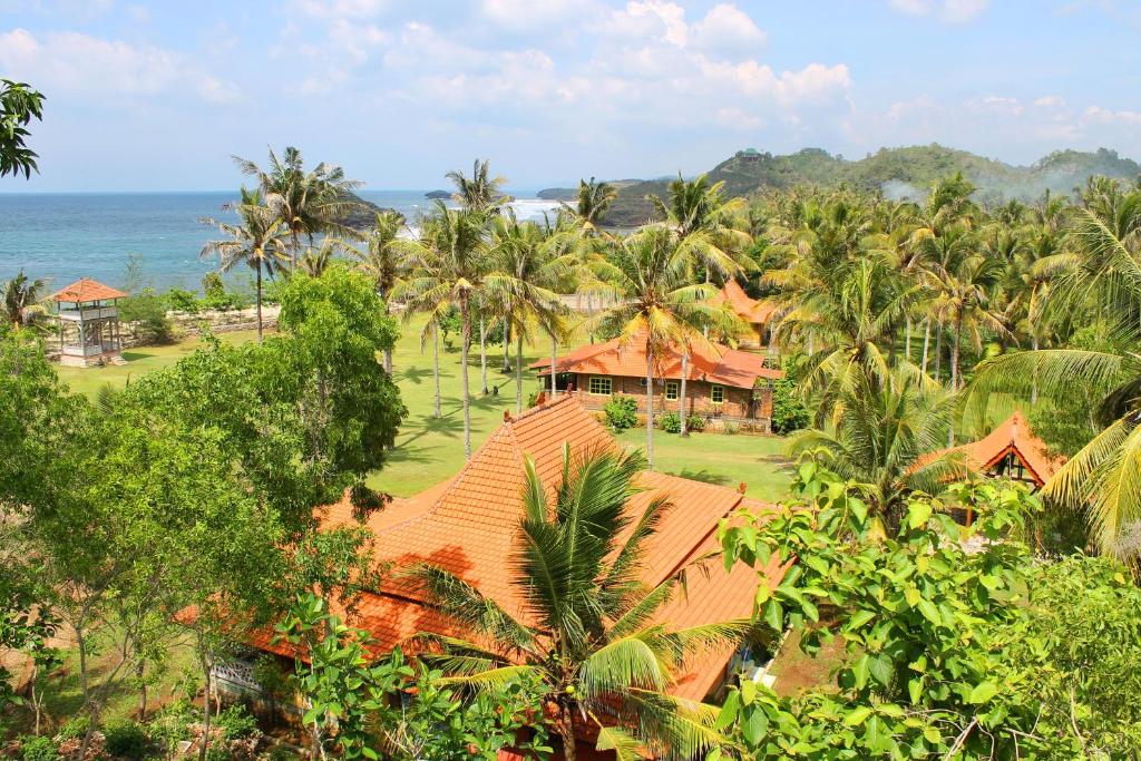 een luchtzicht op een resort met palmbomen en de oceaan bij Desa Limasan Resort in Kalak