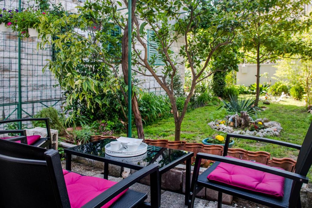 um pátio com uma mesa e cadeiras com almofadas cor-de-rosa em Heavenly corner em Split