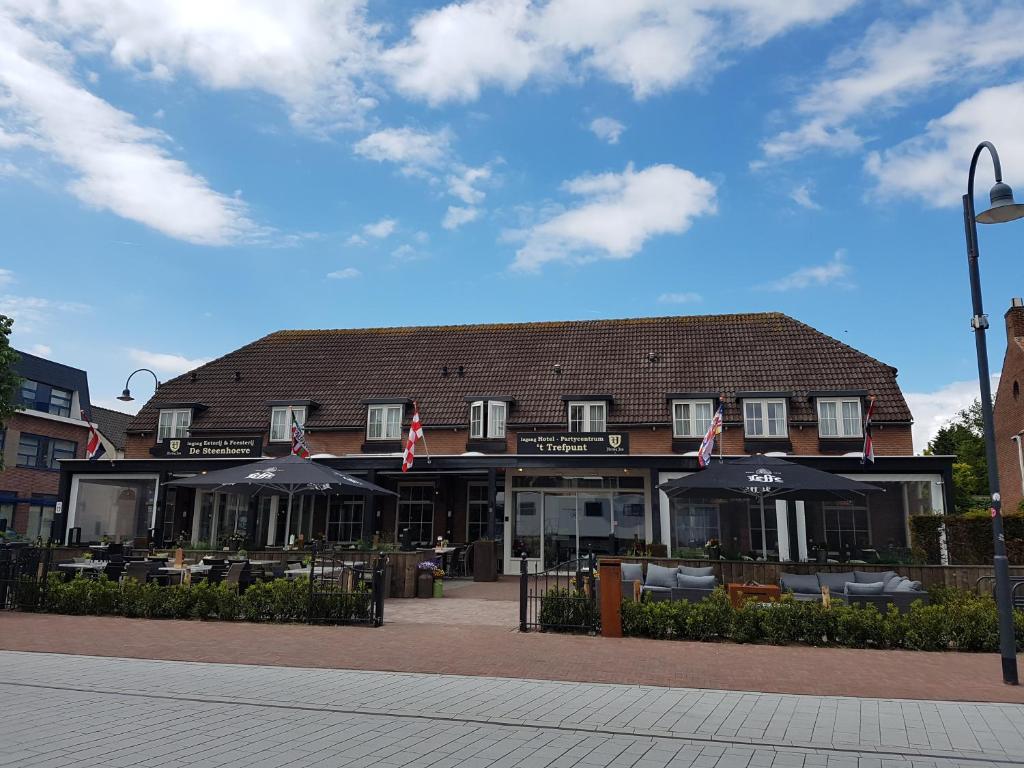 ein Gebäude mit Tischen und Sonnenschirmen davor in der Unterkunft Hotel Restaurant 't Trefpunt in Made