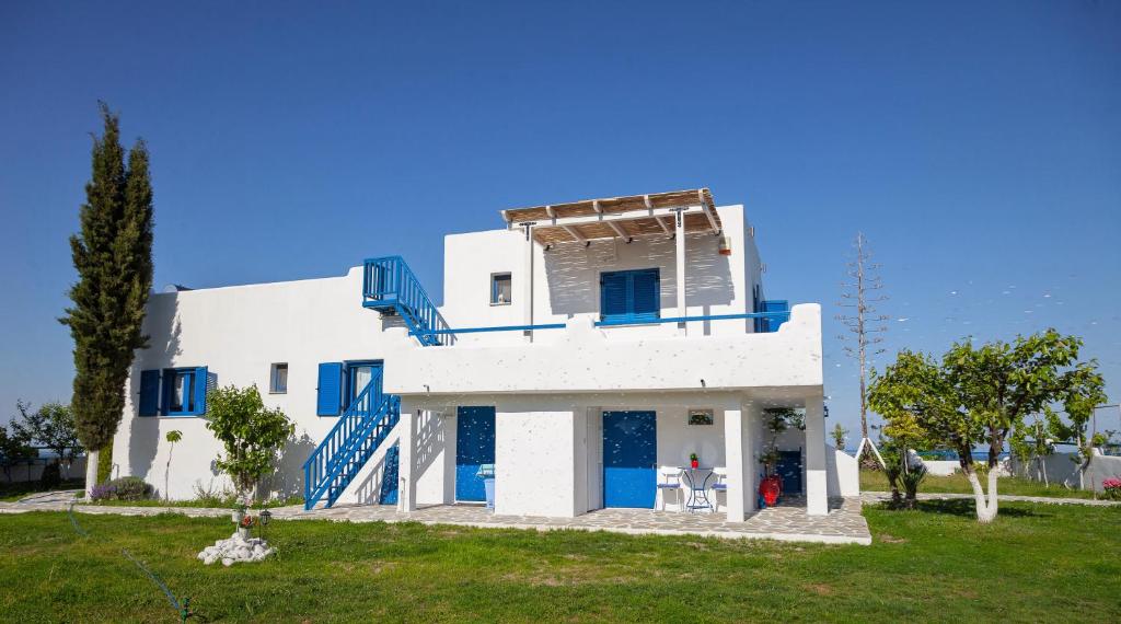 una casa blanca con puertas azules en un campo verde en Navy Greece Villa with swimming pool & sea view en Makrýgialos