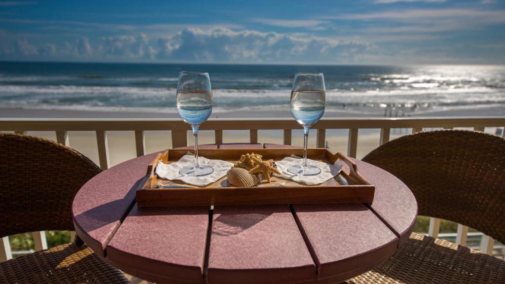 a table with two wine glasses and a tray of food at Family Friendly - Direct Oceanfront Sanibel 303 in Daytona Beach Shores