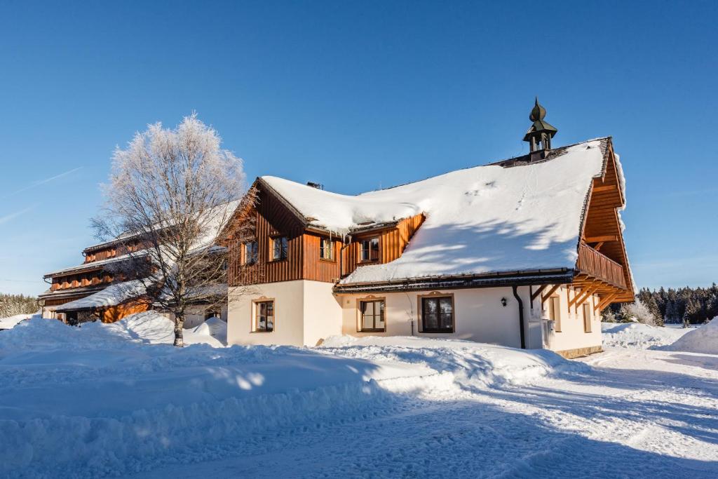 dom pokryty śniegiem z krzyżem na dachu w obiekcie Hotel Rankl w mieście Horská Kvilda