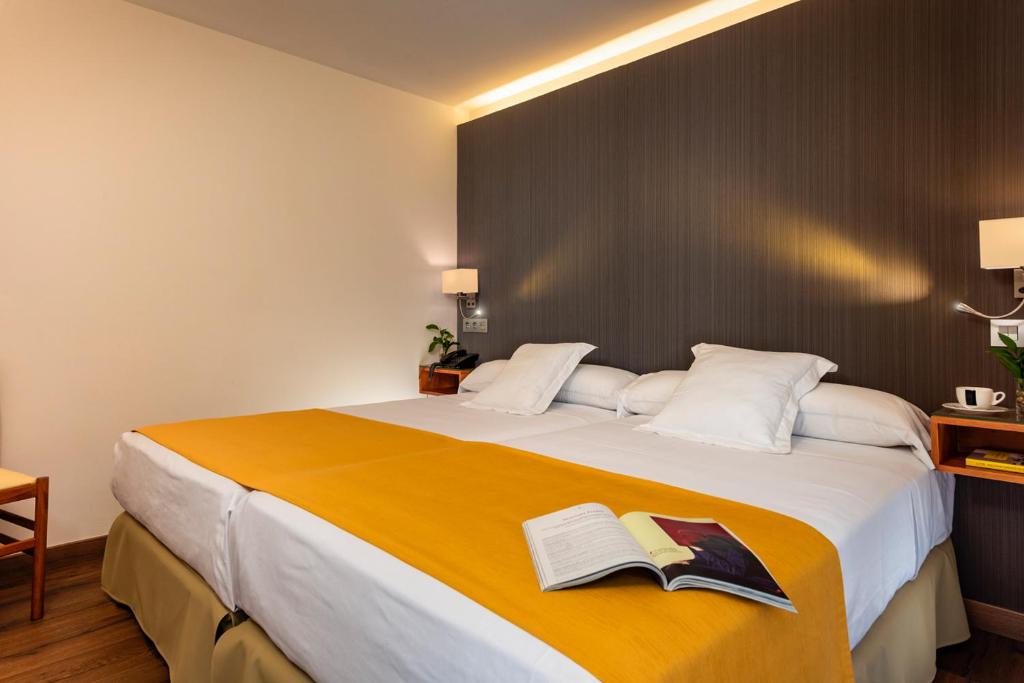 a bedroom with a large bed with two books on it at Hotel de Francia y París in Cádiz