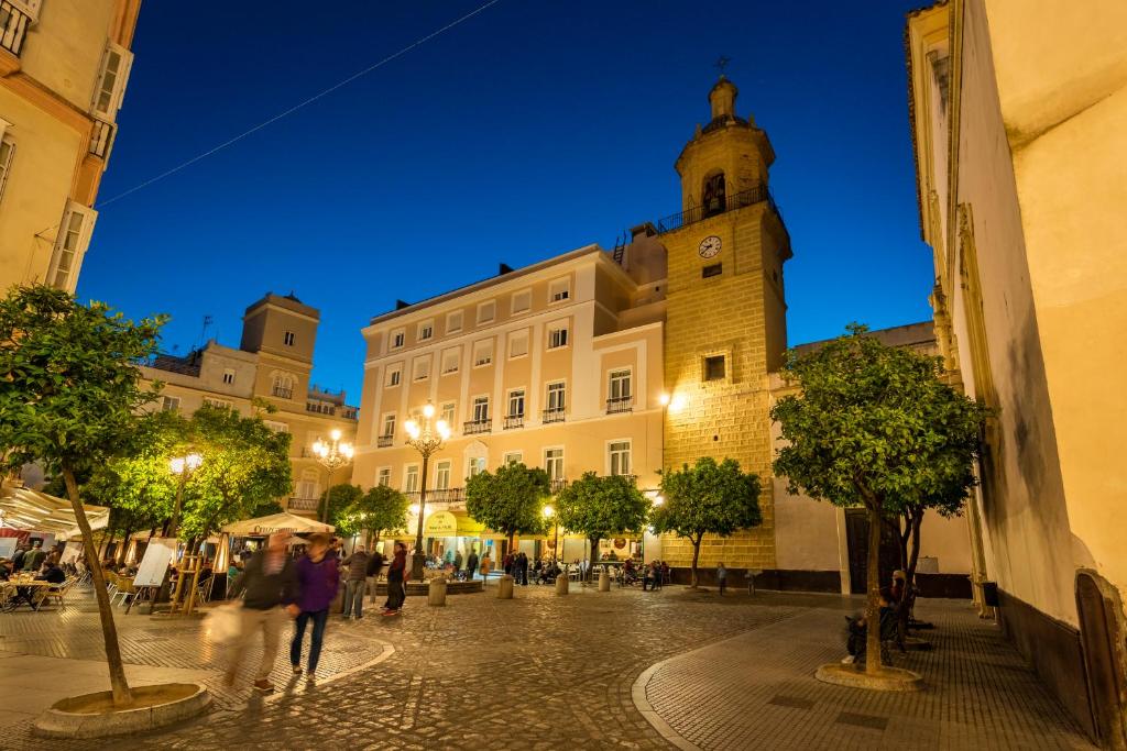 a building with a clock tower in a street at night at Hotel de Francia y París in Cádiz