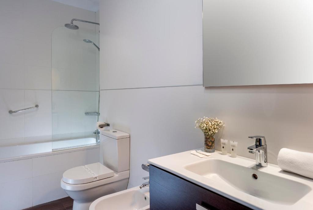a white bathroom with a toilet and a sink at Hotel de Francia y París in Cádiz